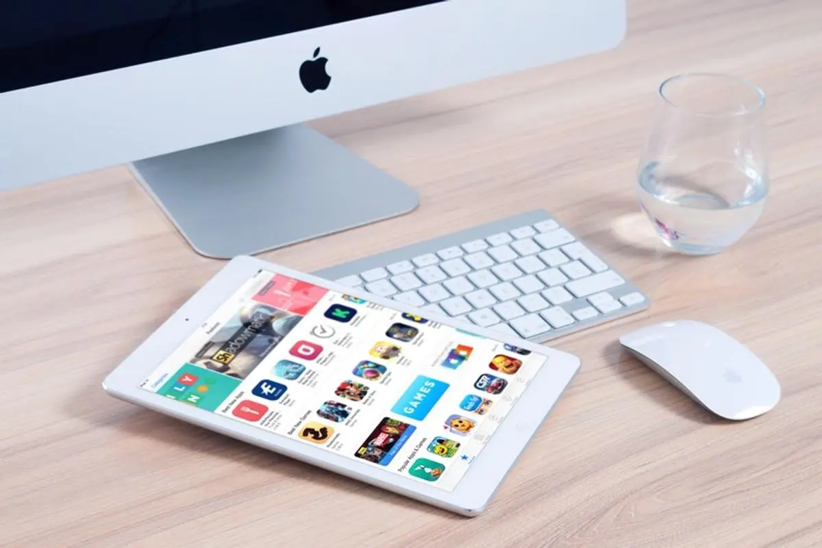 A mobile, glass, keyboard and mouse is placed on the table.