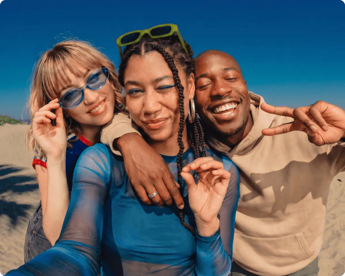 Three friends taking a selfie on a beach wearing fashion apparel