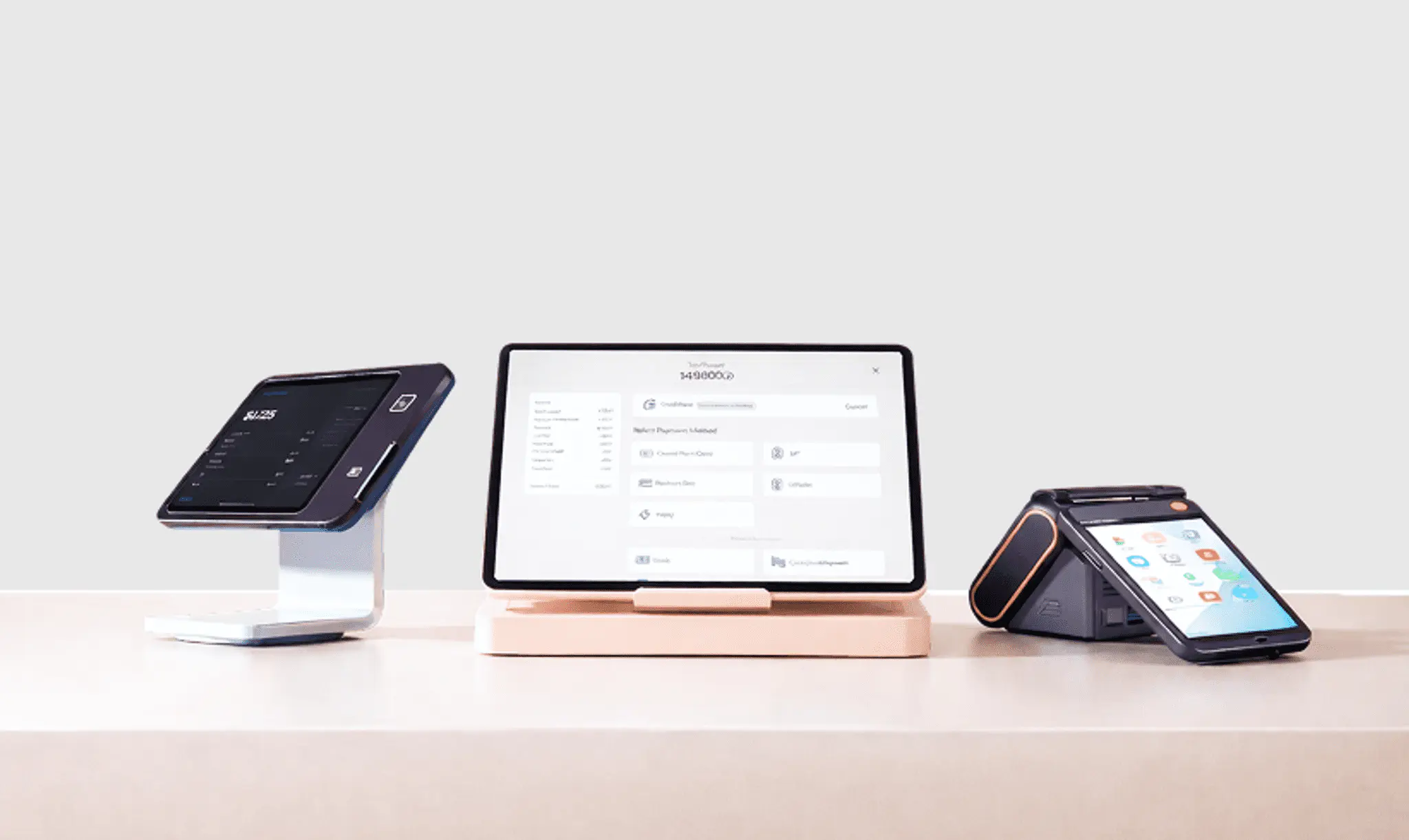 Three POS hardware devices on a counter — a card reader, a tablet with a payment screen, and a handheld terminal