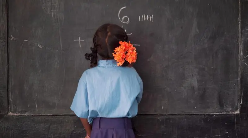 A learner writing on a classroom chalkboard