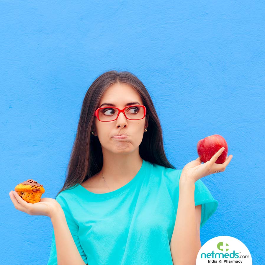 girl holding cup cake in one hand and apple in other hand