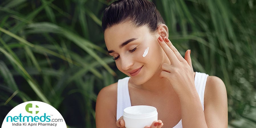 Woman applying cream onto her face