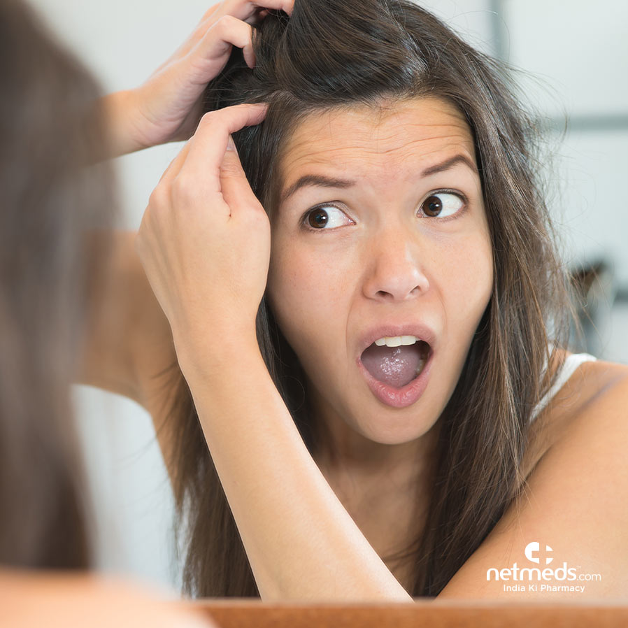 Woman looking at her grey hairs on mirror